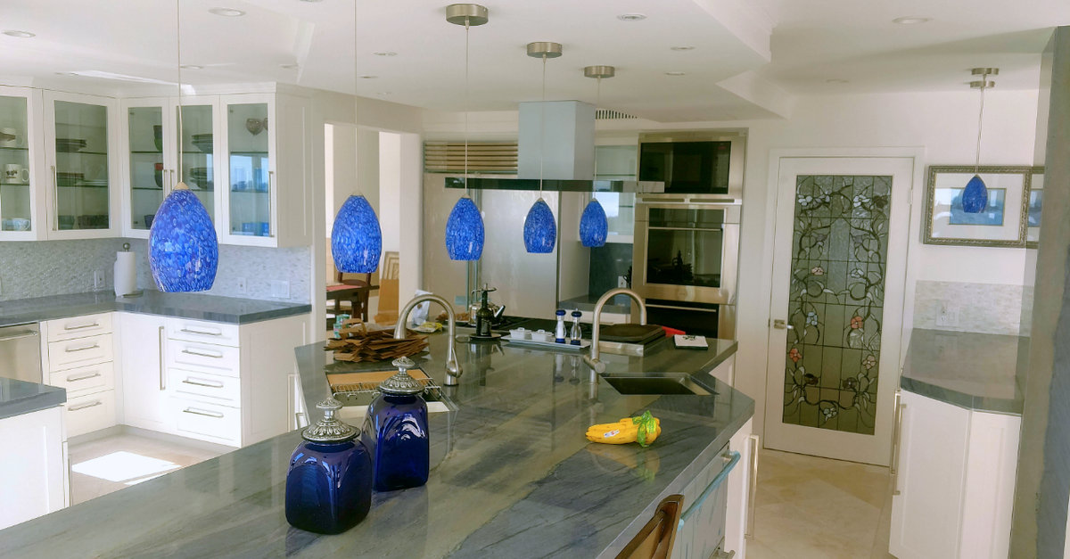 Light-filled Malibu kitchen with a stone island and blue glass pendant lights